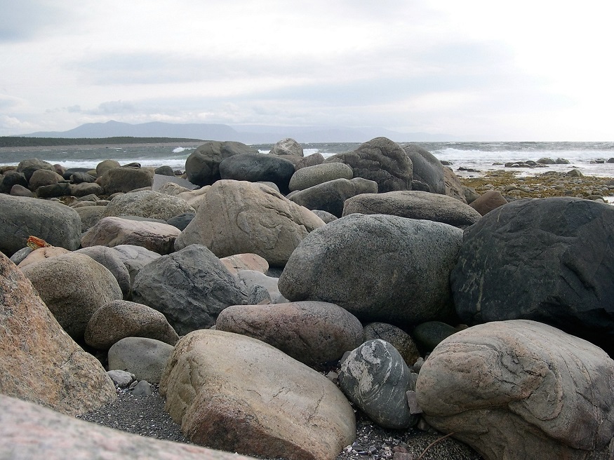 Ground-level view of beach rocks in foreground; ocean in background.