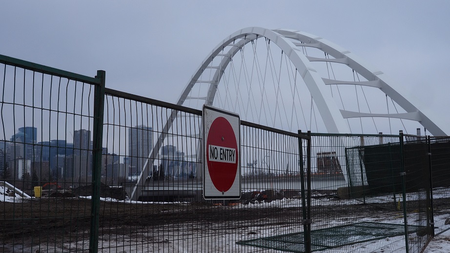 Construction fence with Walterdale Bridge in background.