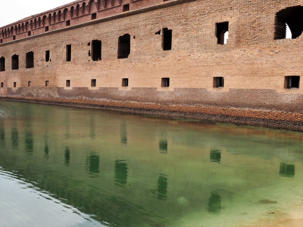 Wall of fort reflected in moat.