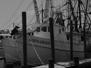 Black and white image of fishing boats tied up at dock.