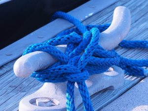 Blue nylon rope around cleat on pier